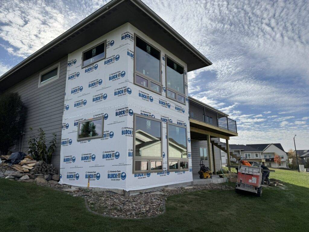 New home under construction with house wrap and windows installed on a Central Iowa lot