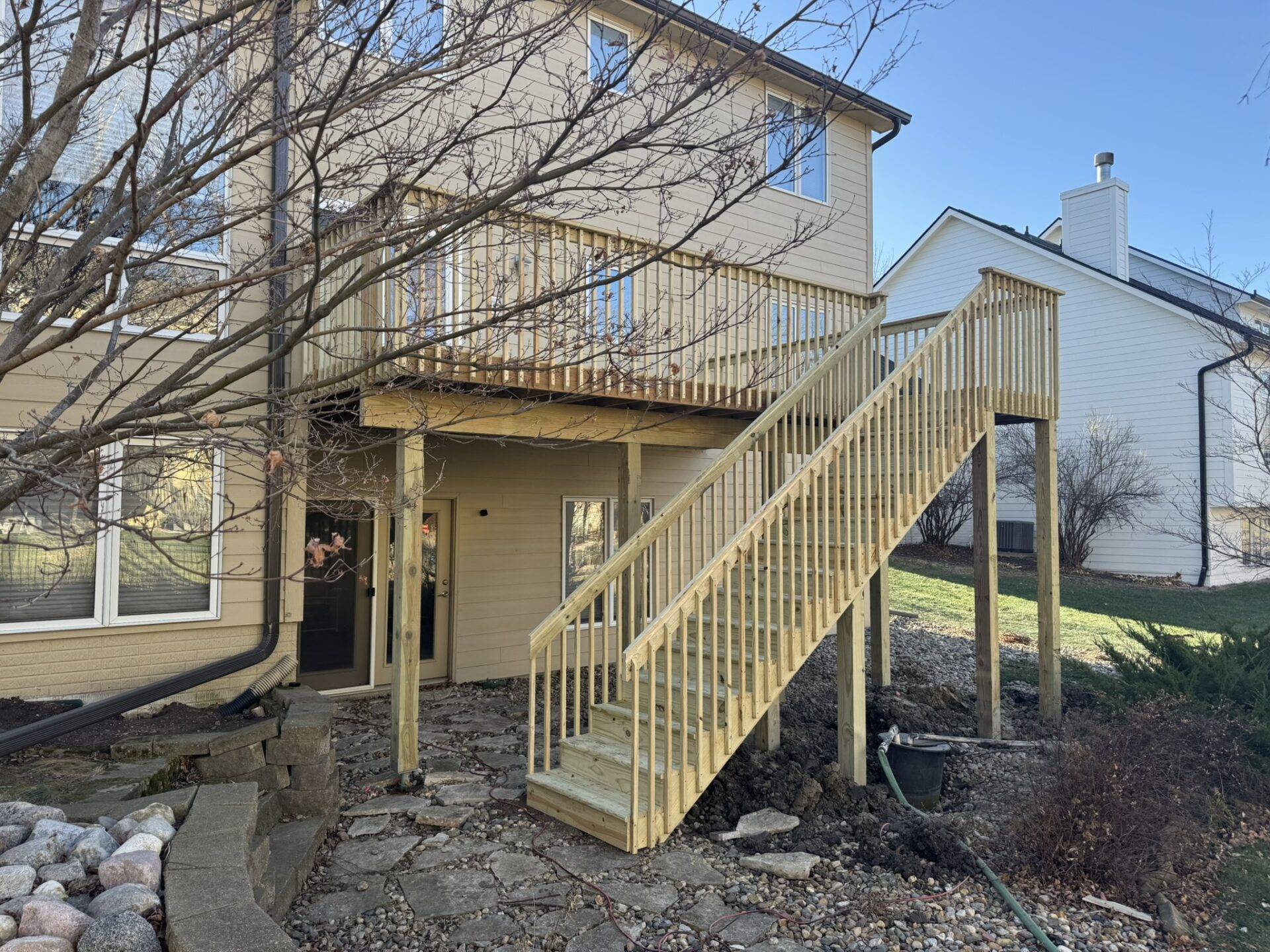 Raised pressure-treated wood deck with 6x6 posts, baluster railing and stairs on a two-story Central Iowa home during deck building