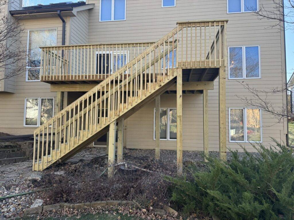 Raised wood deck with long stair run down to grade on a two story Iowa home