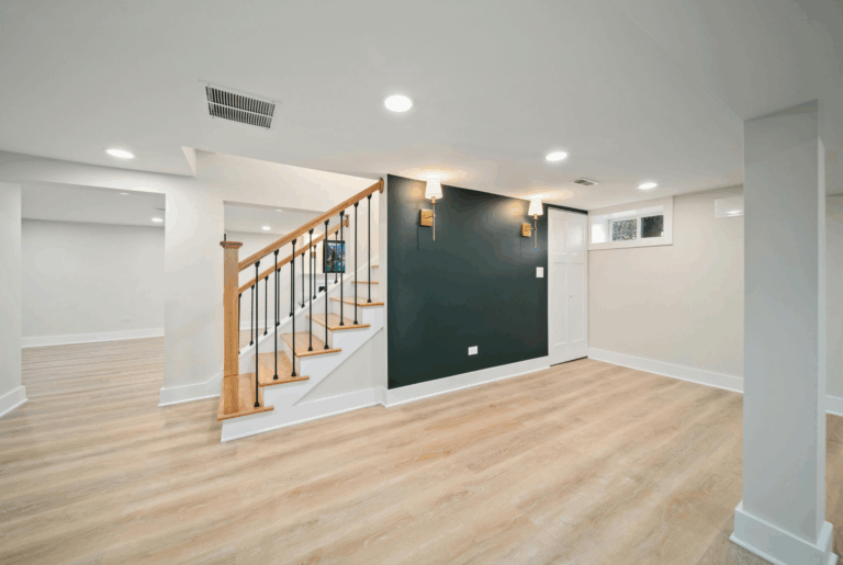 finished basement with luxury vinyl plank flooring, dark green accent wall, gold wall sconces, recessed lighting, and open oak stair railing