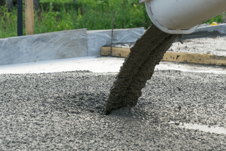 Concrete being poured from a ready-mix truck chute into foundation forms during home addition construction