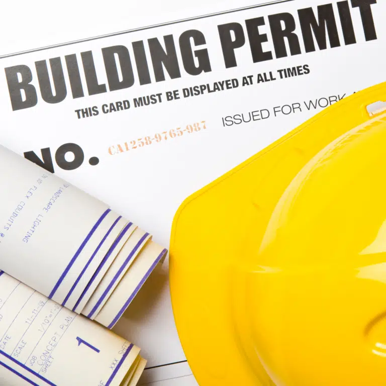 Building permit card with yellow hard hat and rolled construction blueprints for a home addition project