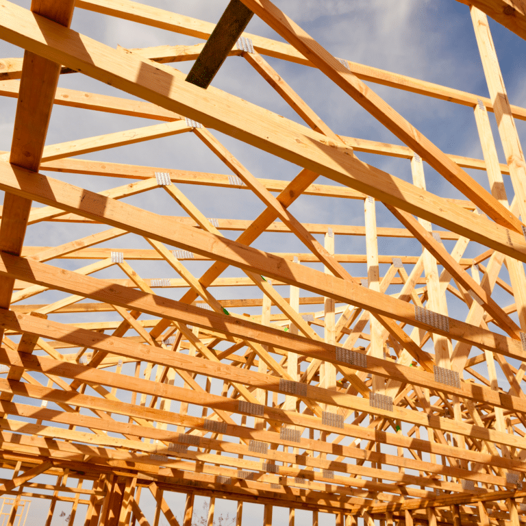 New home construction engineered roof trusses framed against blue sky before sheathing and roofing installation